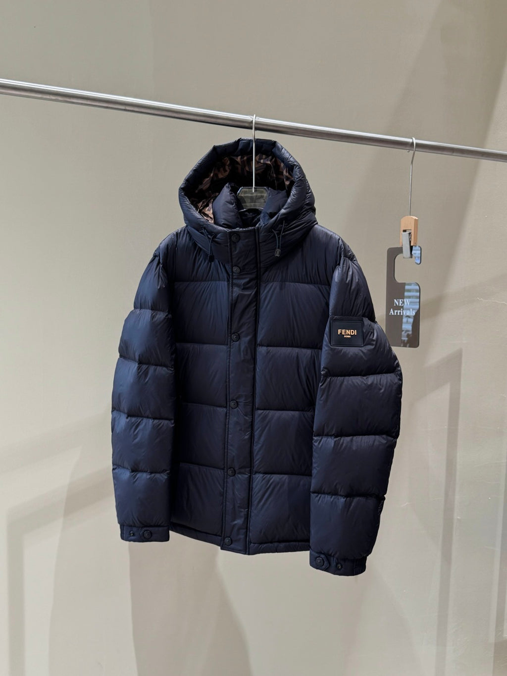 Dark hooded puffer jacket with zipper front, quilted texture, and ribbed cuffs.