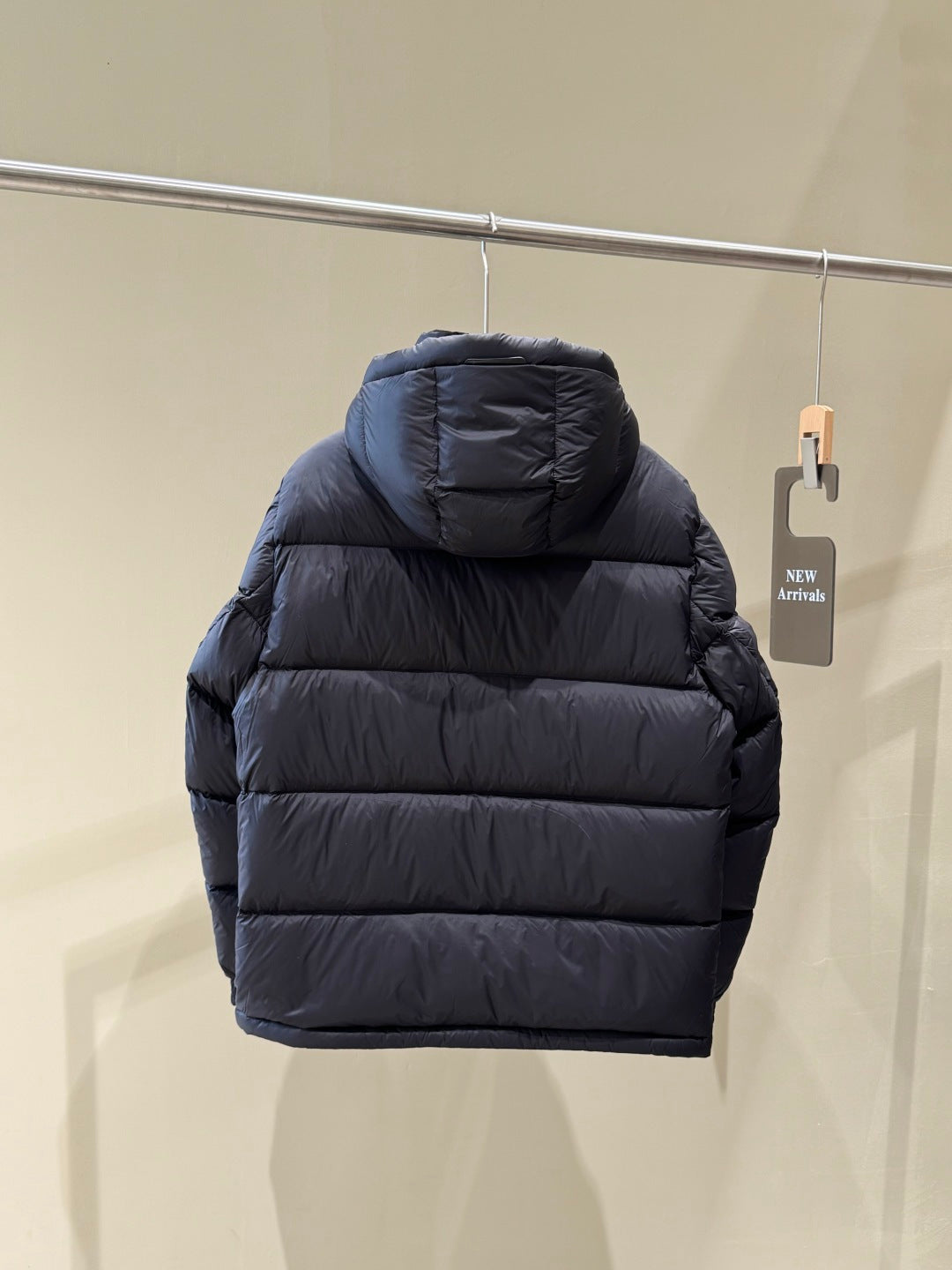 Dark hooded puffer jacket back view with quilted stripes and stand-collar hood.