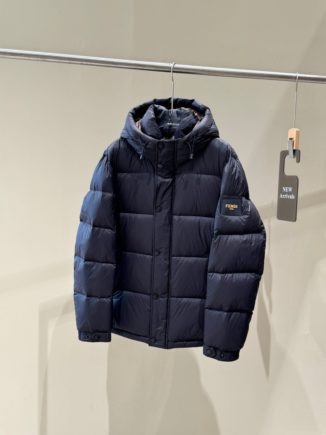 Dark hooded puffer jacket with zipper front and small Fendi logo patch on chest.