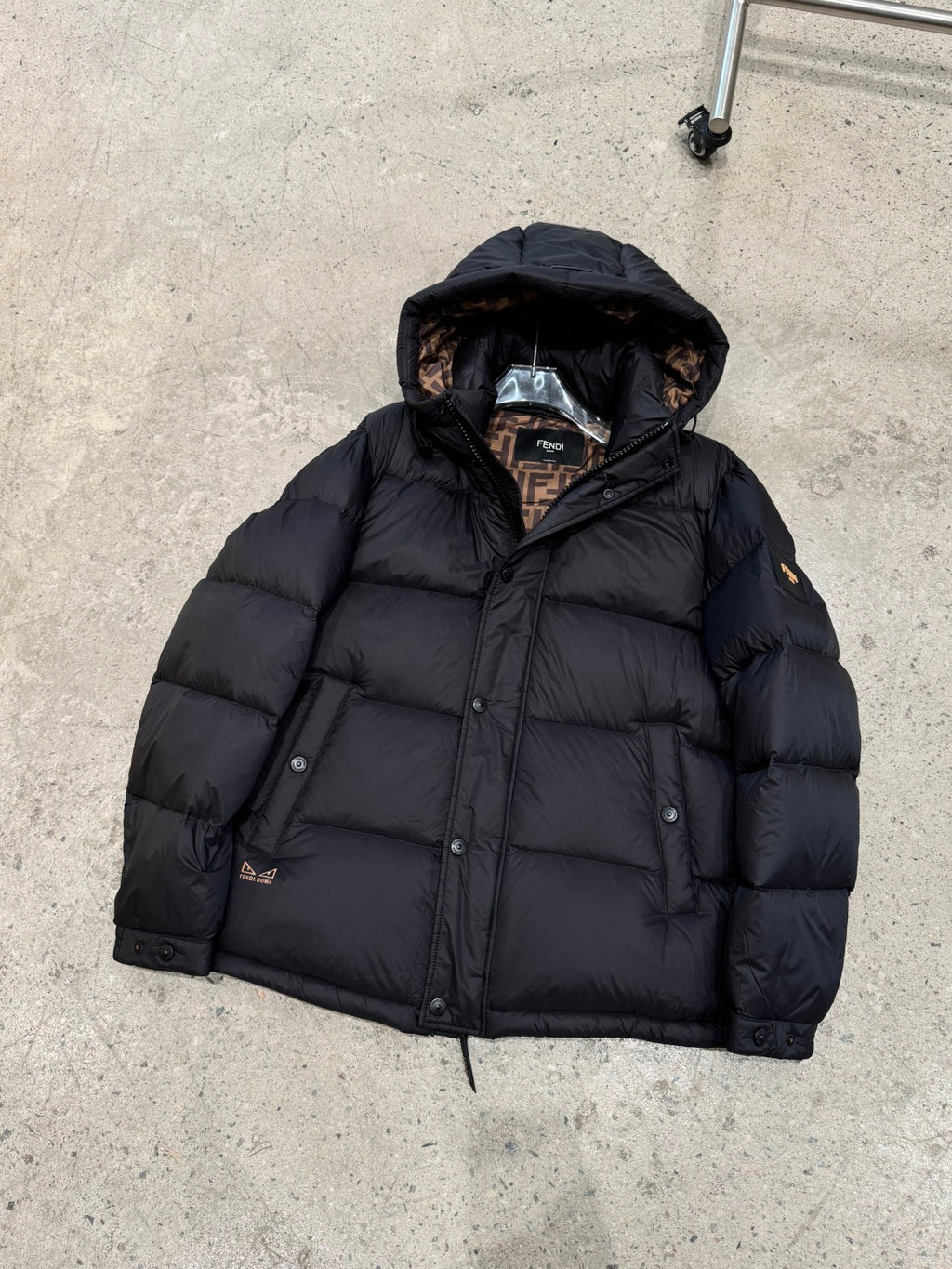 Dark hooded puffer jacket with zipper front and quilted insulation, laid flat.