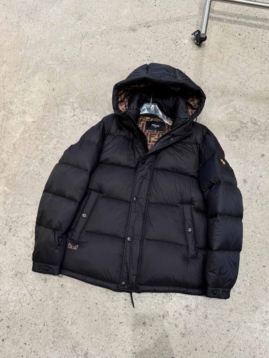 Dark hooded puffer jacket with zipper front and quilted insulation, laid flat.