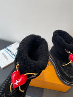 Black plush-lined ankle boot with gold laces and red heart charm accent