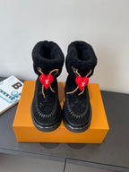 Black monogram ankle boots with plush lining, gold trim, and red heart charms