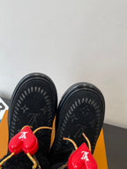 Black monogram ankle boots with red heart charms and gold-trimmed laces