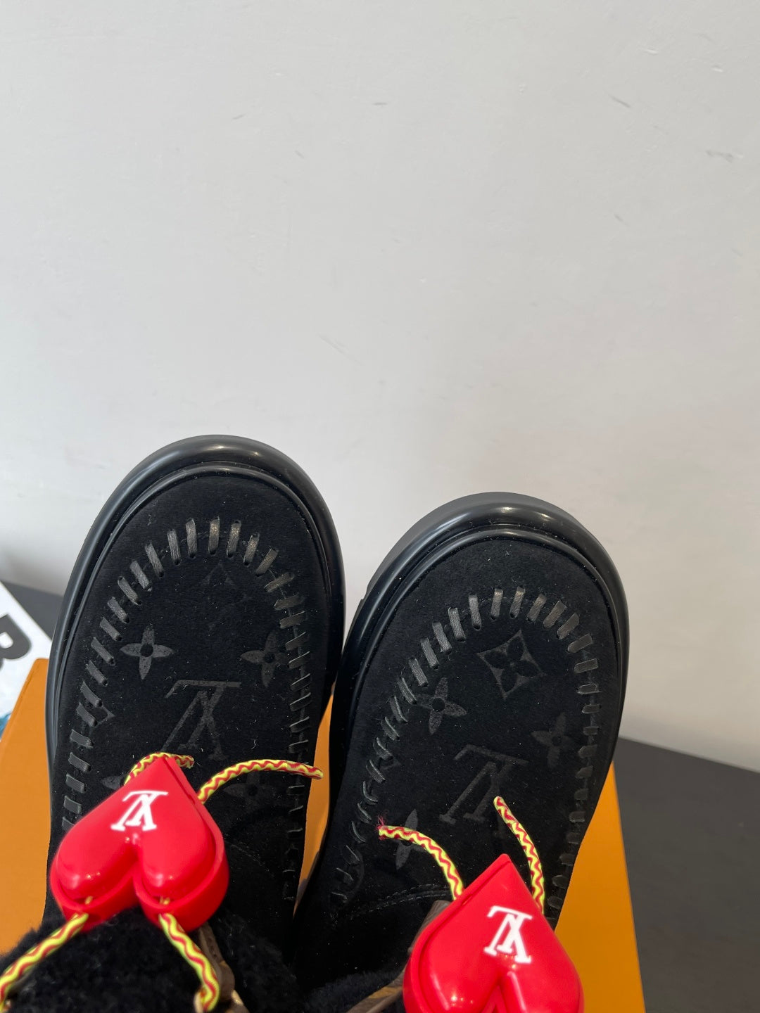 Black monogram ankle boots with red heart charms and gold-trimmed laces