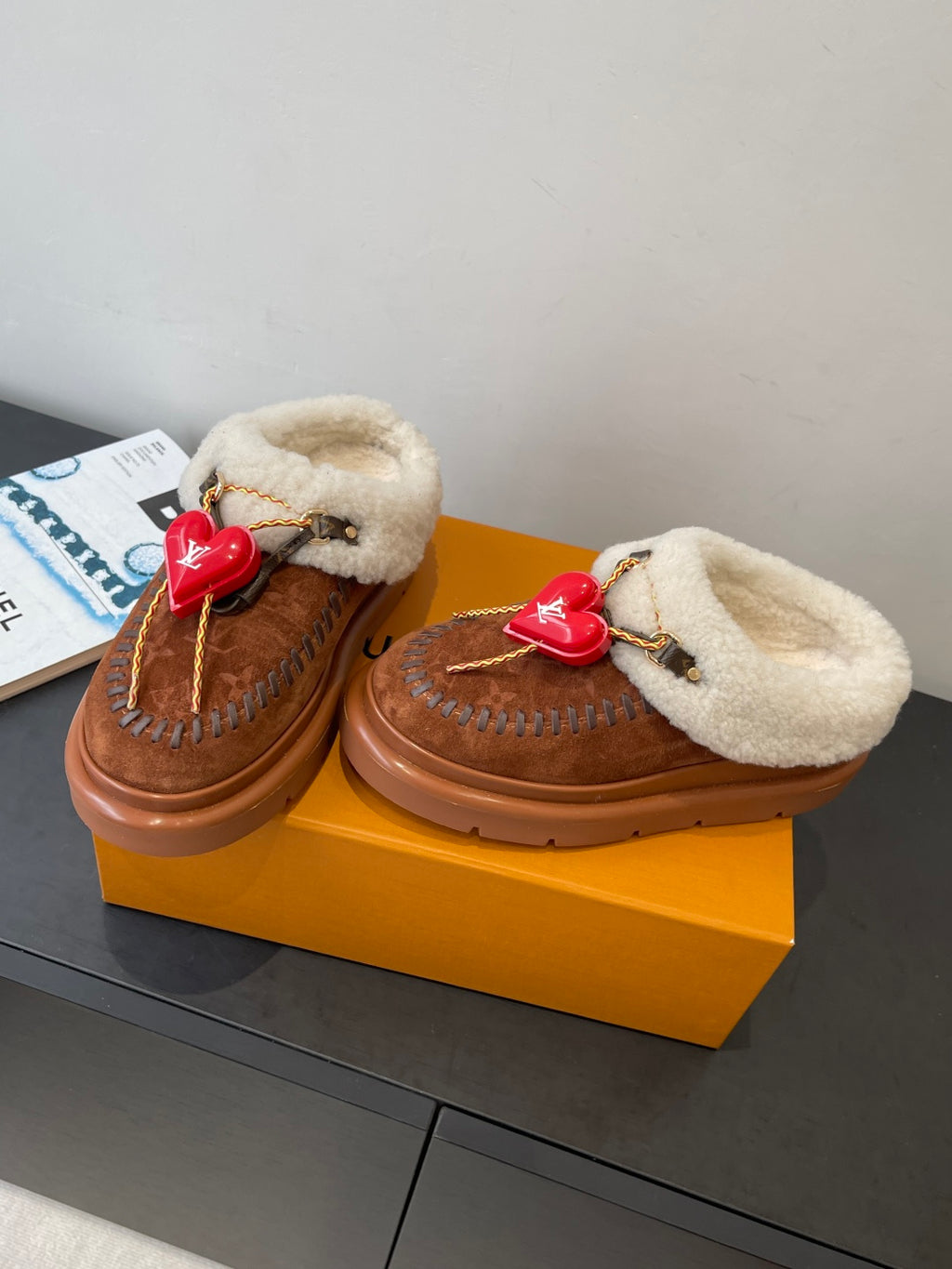 Pair of brown suede slip-on shoes with cream shearling straps and red heart LV charms