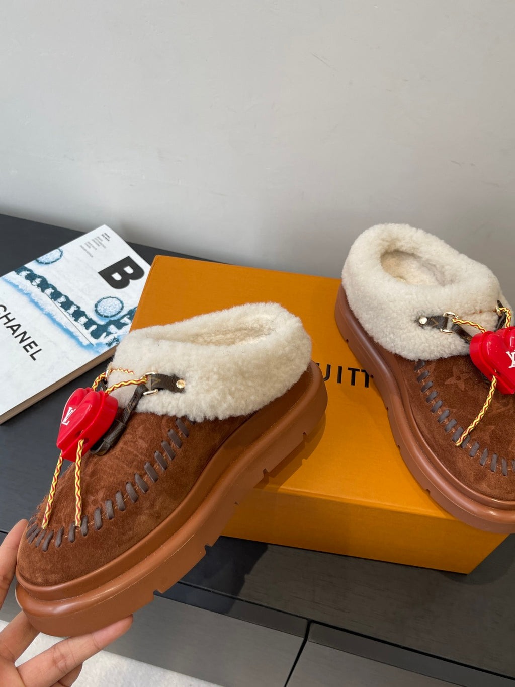 Pair of brown suede slides with cream shearling straps and red heart LV charms
