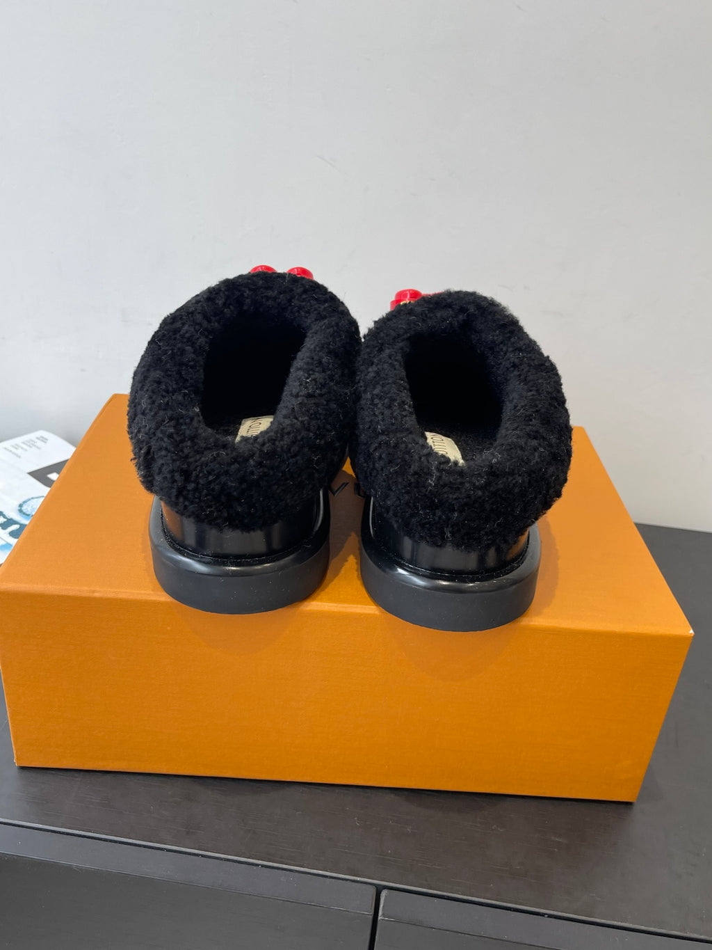 Black shearling slip-on shoes back view with red heart LV charm tabs