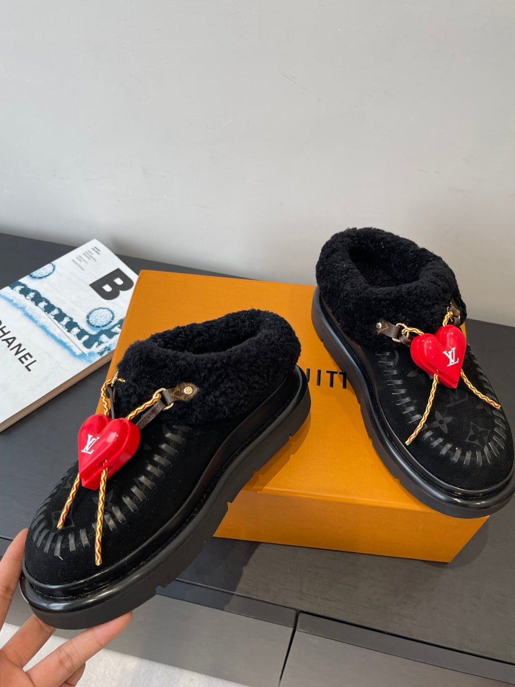 Pair of black shearling slip-on shoes with red heart LV charms and braided laces