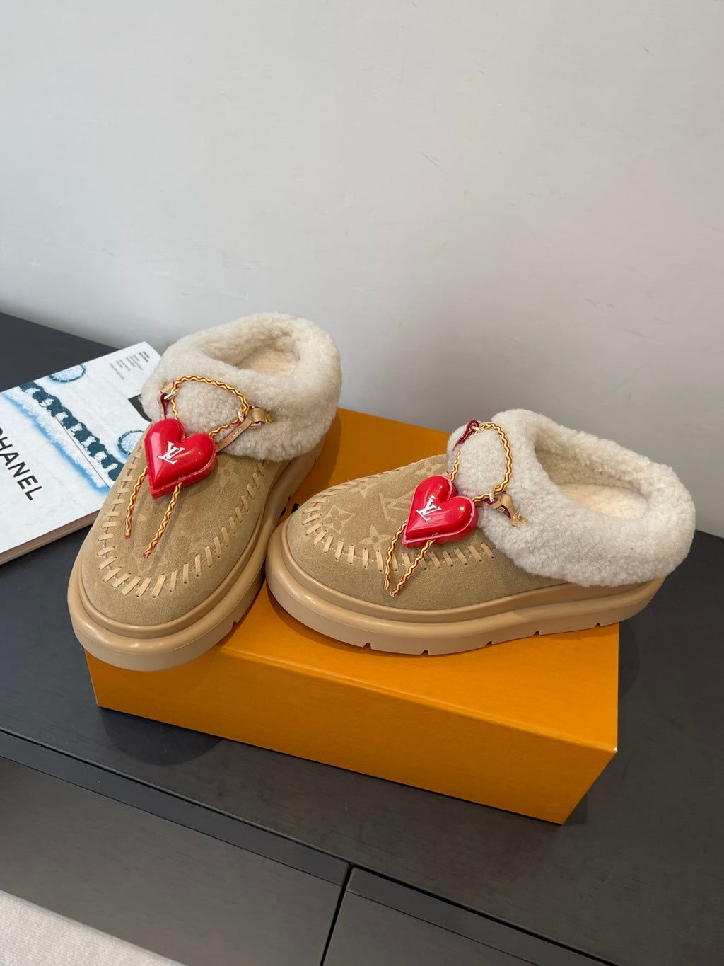 Tan shearling-lined slip-on shoes with gold chain trim and red heart charm pair view