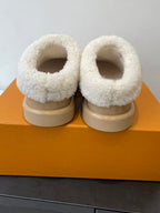 Pair of tan slip-on shoes with cream shearling cuffs and rounded toe openings