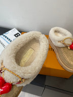 Shearling-lined tan slip-on shoes with embossed insole and gold chain detail