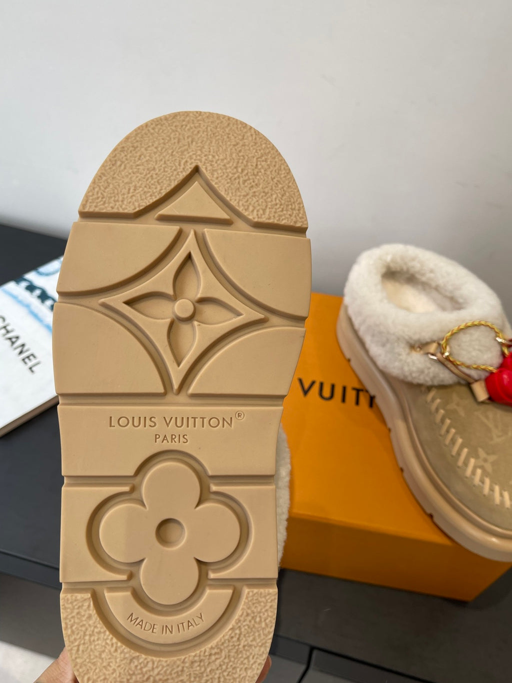 Tan outsole view of shearling slip-on shoes with embossed monogram flower and text