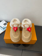 Shearling-lined tan slip-on shoes with gold chain trim and red heart charm details