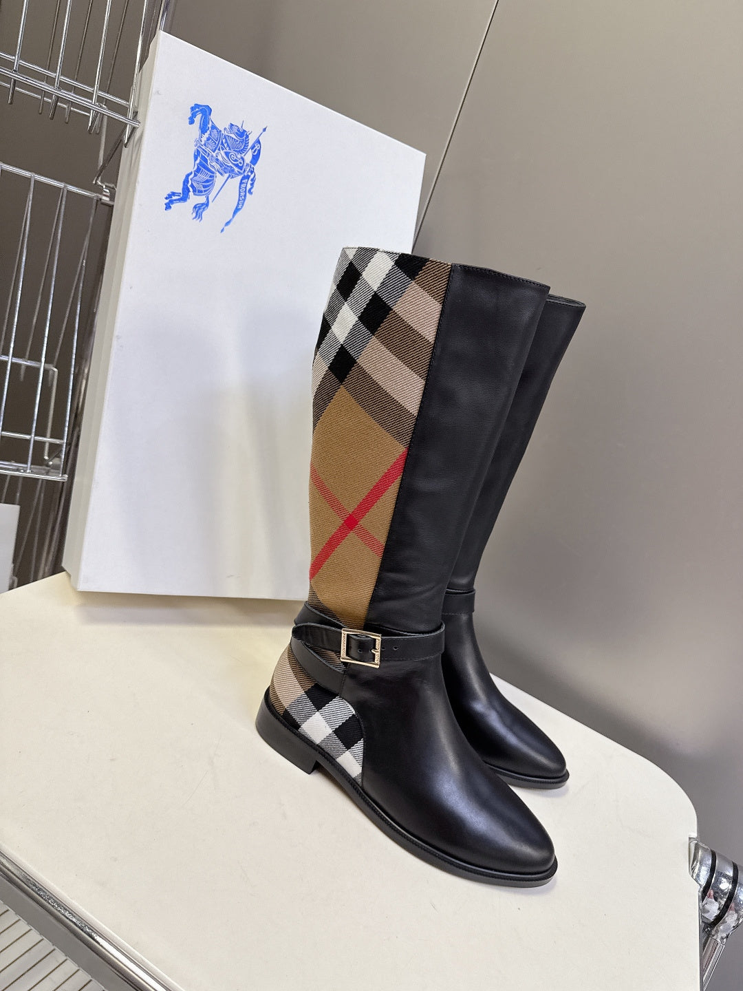 Burberry black knee-high leather boot with plaid panel and buckled ankle strap