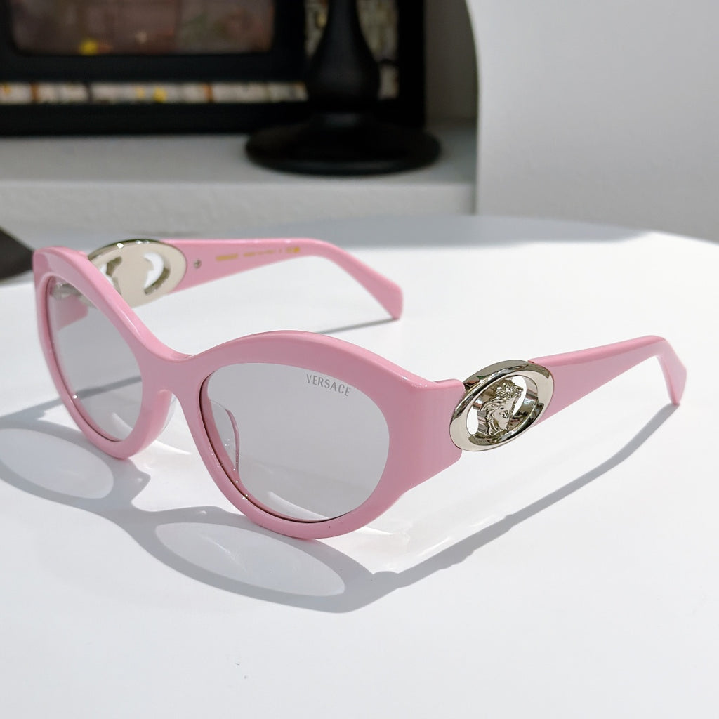 Pink cat-eye sunglasses with gold medallion logo detail and tinted lenses