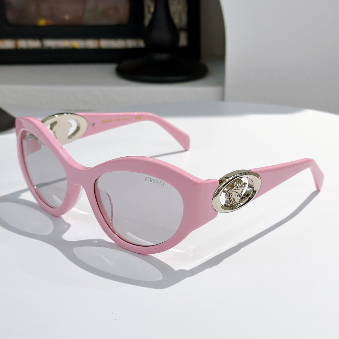 Pink cat-eye sunglasses with gold medallion logo detail and tinted lenses