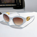 White cat-eye sunglasses with gold medallion logo detail and warm brown tinted lenses