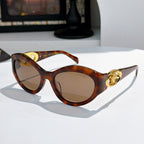 Tortoiseshell cat-eye sunglasses with gold medallion logo detail and amber tinted lenses