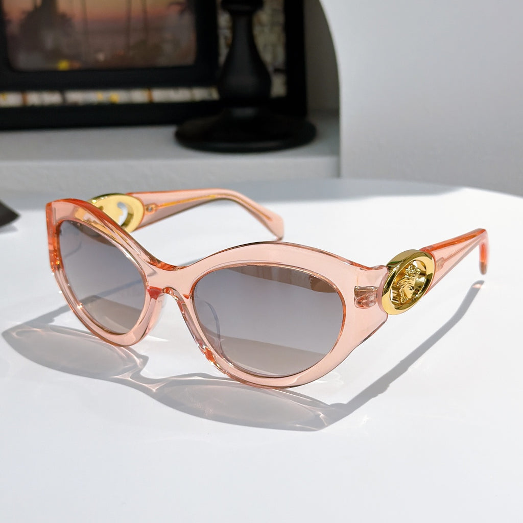 Light pink round cat-eye sunglasses with gold medallion logo detail and tinted lenses