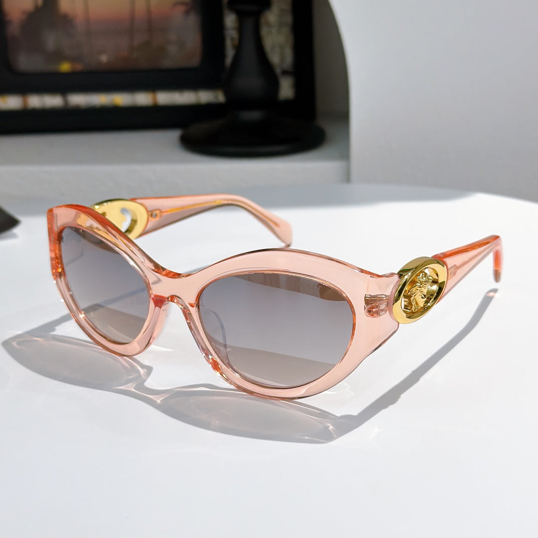 Light pink round cat-eye sunglasses with gold medallion logo detail and tinted lenses