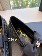 Close-up of black Chanel flats with bow; interior shows CHANEL text