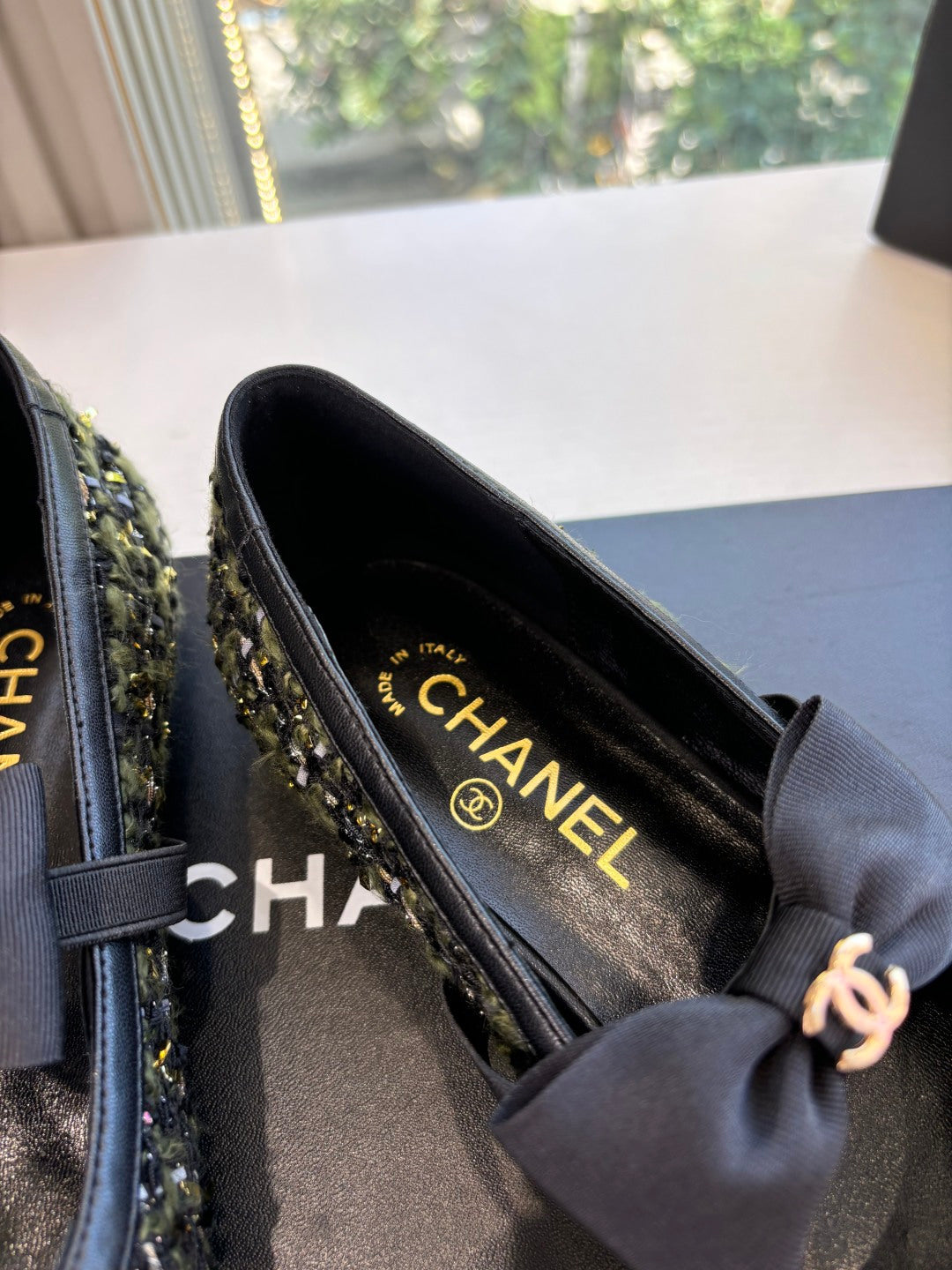 Close-up of black Chanel flats with bow; interior shows CHANEL text