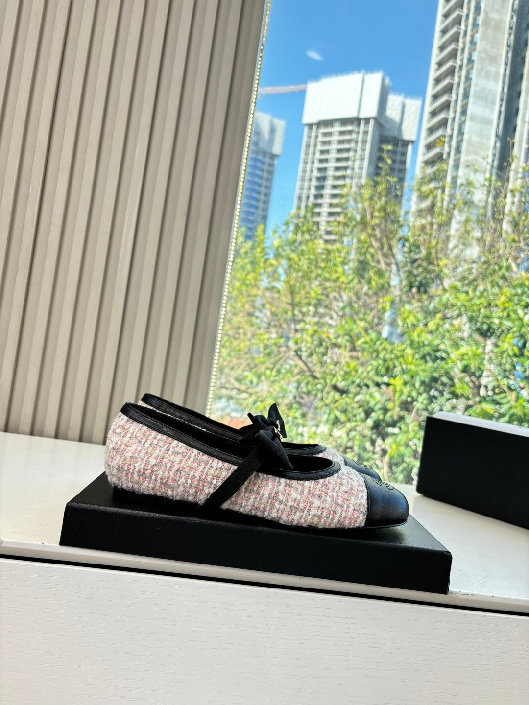 Black and tweed ballet flat with ribbon bow, displayed on a black shoe box