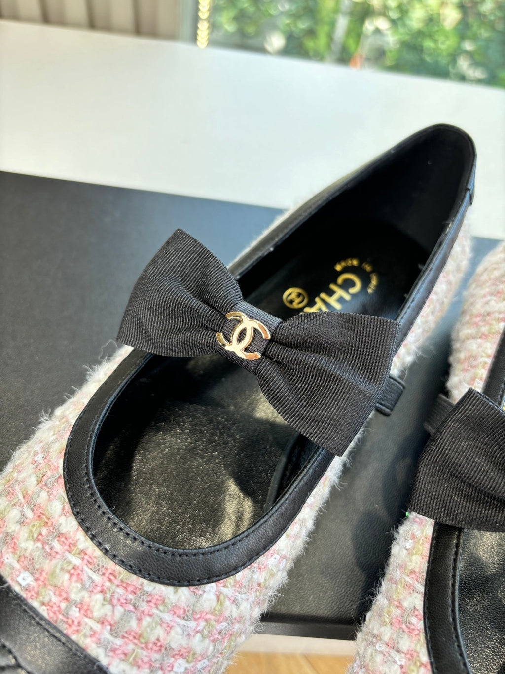 Close-up of black and tweed ballet flat with oversized gray ribbon bow and logo