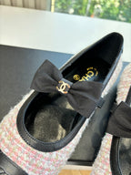 Close-up of black and tweed ballet flat with oversized gray ribbon bow and logo
