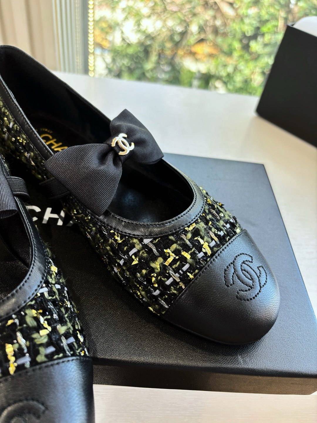Close-up of black Chanel flats with bow and multicolor tweed toe panel