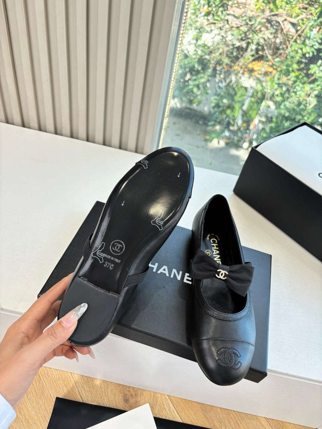 Black leather flat shoe pair with bow and Chanel CC logo on insole