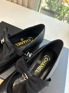 Black satin-lined flats with bow and Chanel logo on insole