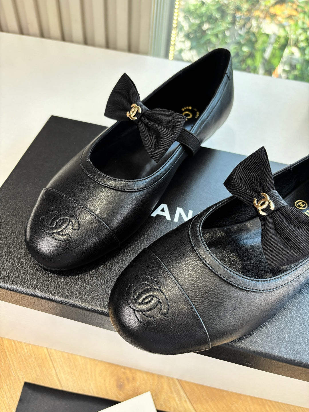 Black leather ballet flats with bow and Chanel CC logo on toe cap