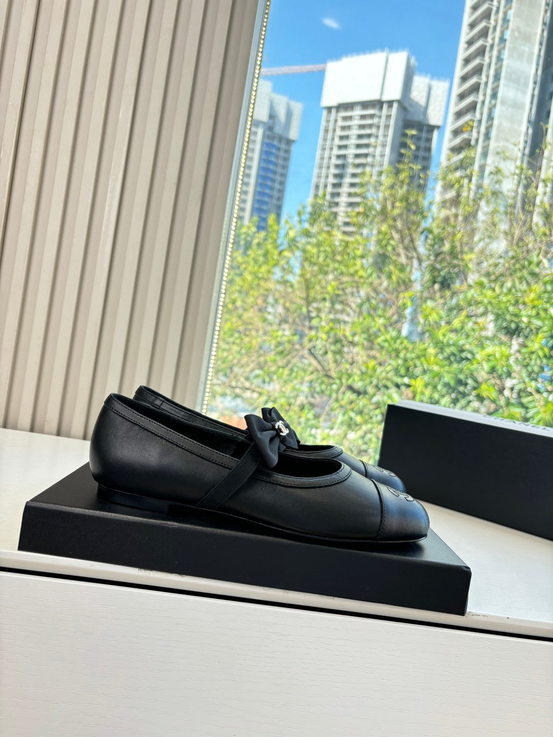 Black leather loafers with bow detail on top, on black shoebox