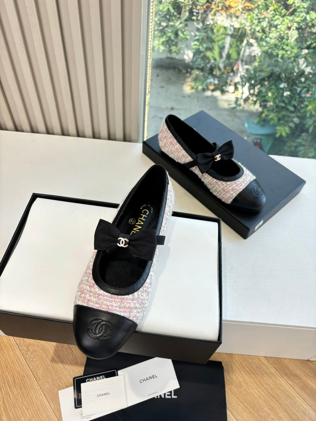 Pair of black and tweed ballet flats in open gift box, with ribbon bow on top