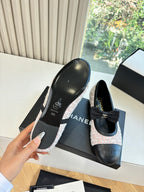 Black leather ballet flats with tweed trim, shown from side angle