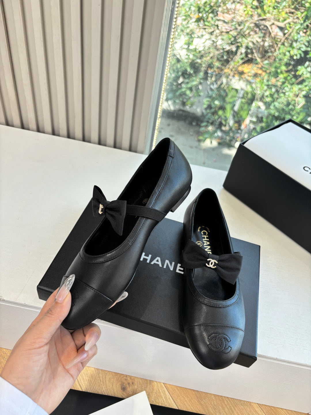 Black leather ballet flats with bow, Chanel CC emblem, and cushioned insole