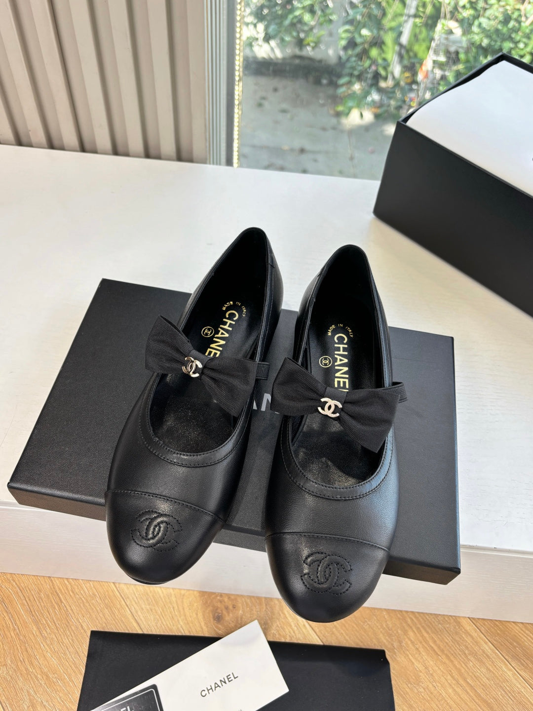 Pair of black leather ballet flats with front bow and Chanel CC logo on toe