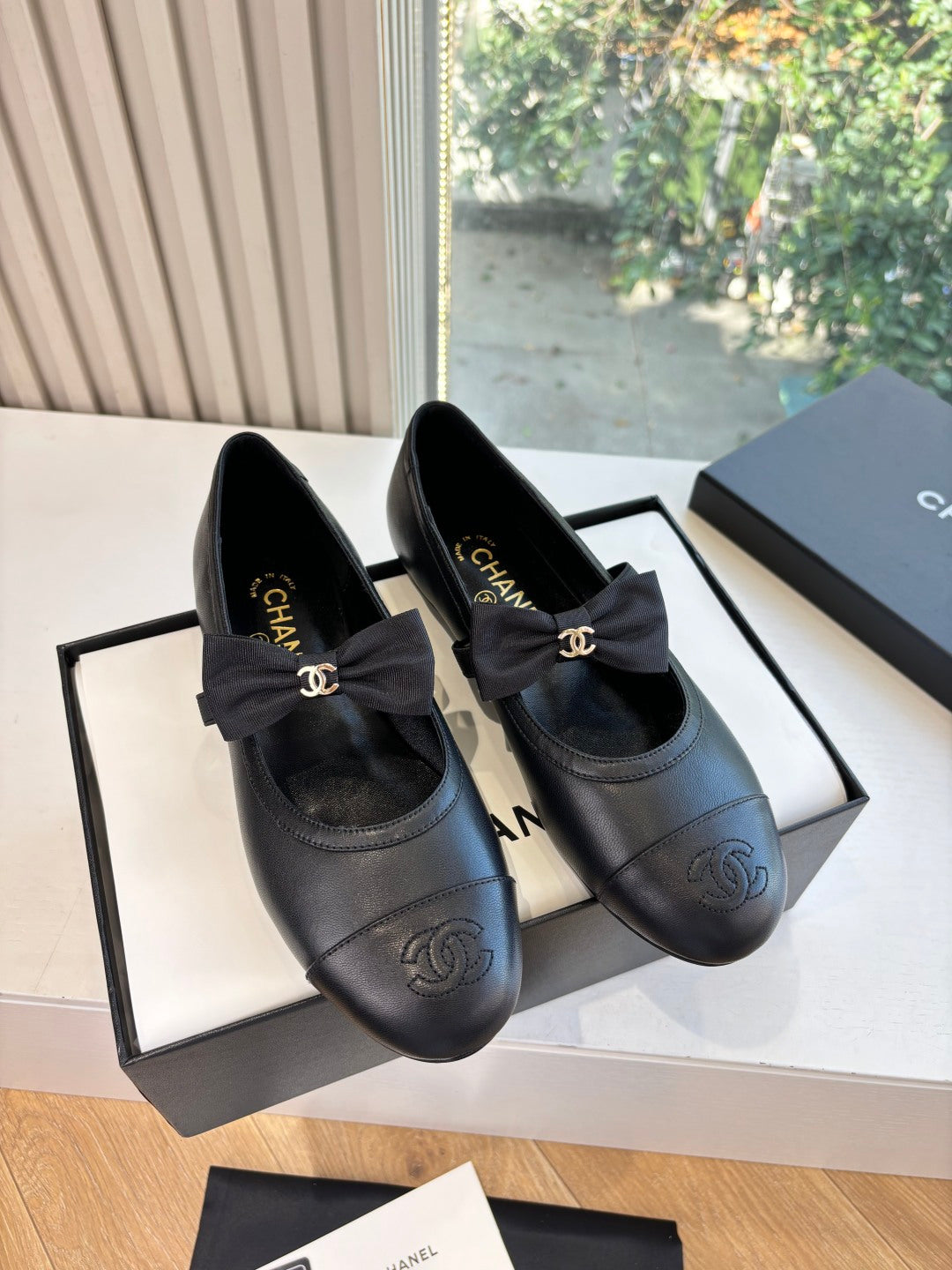 Black leather ballet flats with bow and gold Chanel CC logo detail