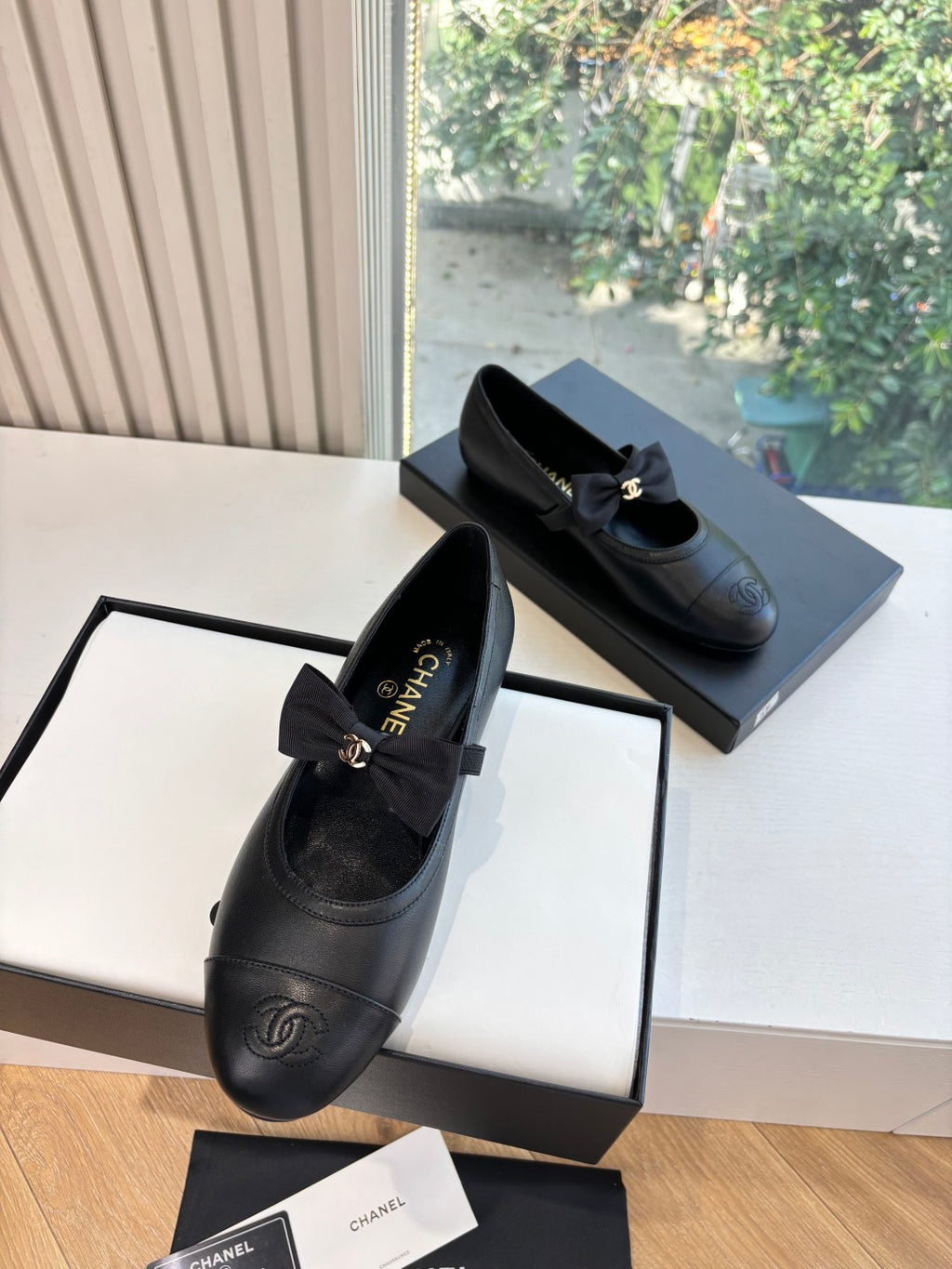 Black leather flats with bow tie, Chanel CC emblem on toe, and low heel