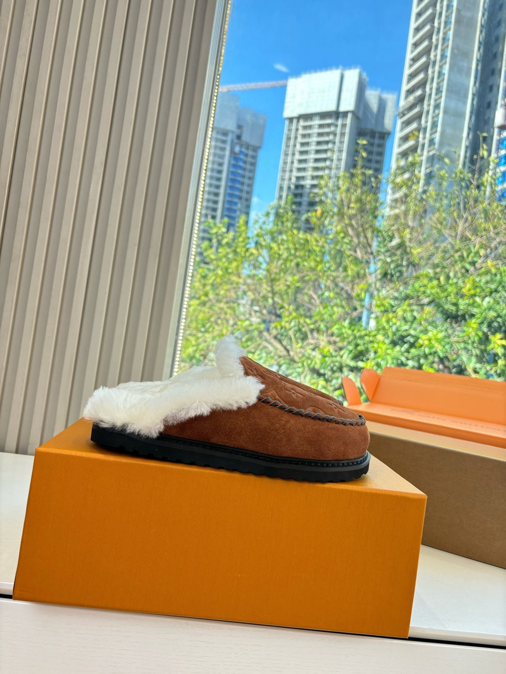 Brown monogram suede shearling slipper with white trim, side view