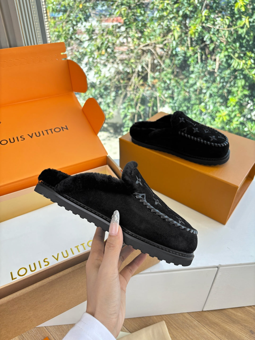 Black Louis Vuitton monogram slip-on slippers on a box, side view