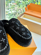 Close-up of black Louis Vuitton monogram slippers with plush upper and stitched trim