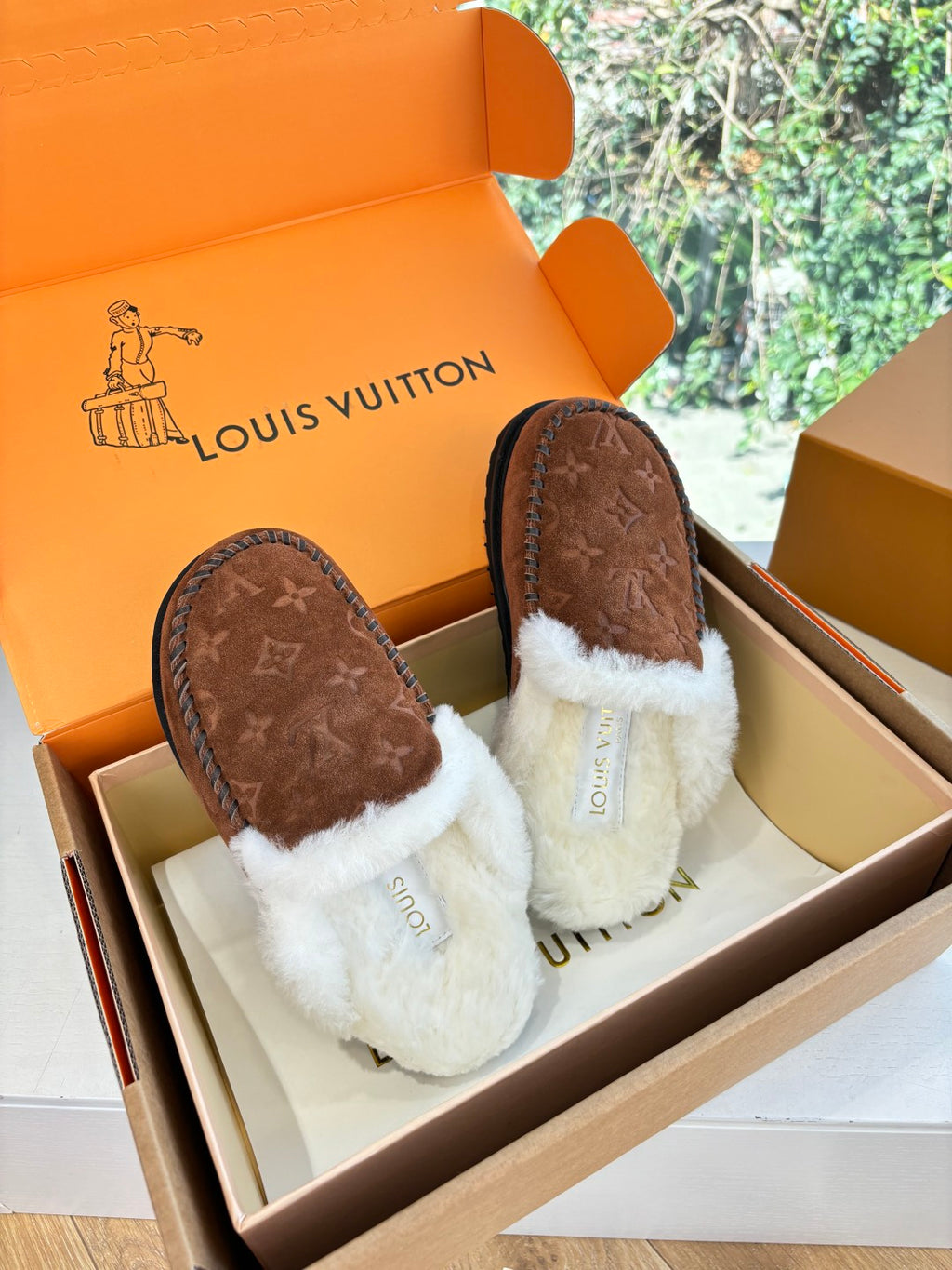 Brown monogram suede slippers with white fleece trim and stitched black edge