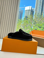 Black Louis Vuitton monogram slip-on slipper resting on an orange shoebox