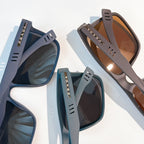 Sunglasses with blue and brown frames and tinted lenses, close side views