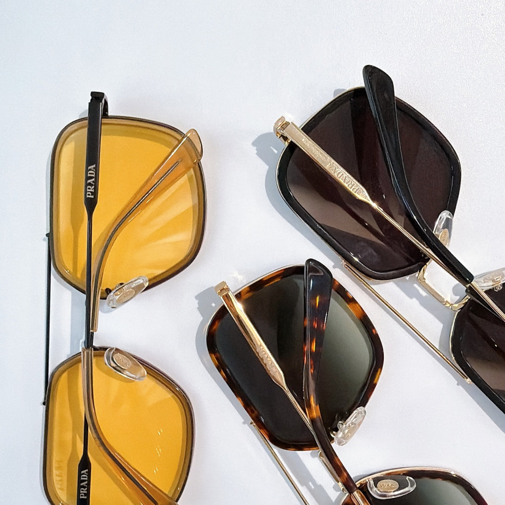 Prada sunglasses set with yellow and dark-tinted lenses on gold-tone frames