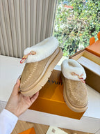 Tan Louis Vuitton shearling loafer, hand-held side view with white fur top and front strap