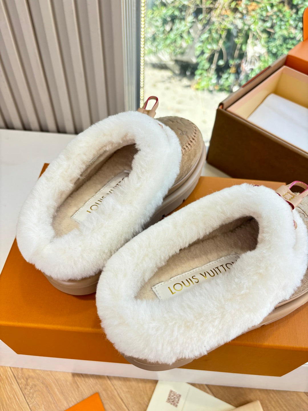 Louis Vuitton tan shearling loafers, close-up of white fur lining and logo front strap